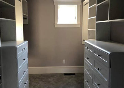 picture of a closet space with built in white dressers and shelves