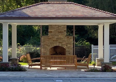 picture of pavilion with wood furniture by an outside chimmey