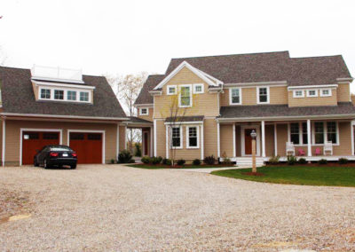 picture of the front of a large house with tan shingles with attached garage