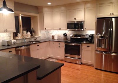 picture of a large kitchen with white cabinet and dark granite countertops