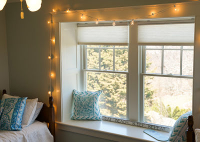picture of a room with 2 twin beds with a double window with lights hanging on the trim- ocean getaway