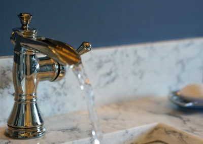 picture of a bathroom faucet with running water- ocean getaway