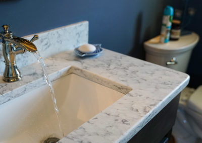 picture of a bathroom faucet with running water in a granite countertop-ocean getaway